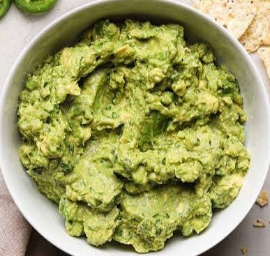 Fresh homemade guacamole in white bowl with tortilla chips - organic avocado SA